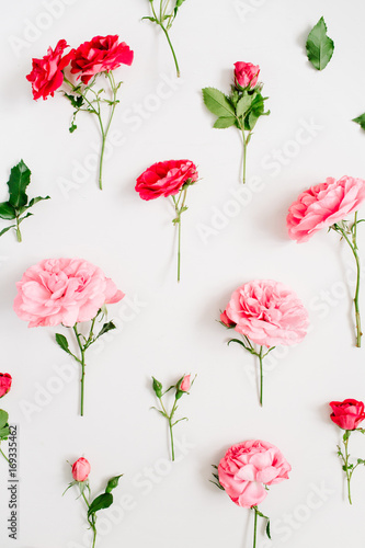 Floral pattern made of pink and red roses  green leaves  branches on white background. Flat lay  top view. Valentine s background. Floral background. Pattern of flowers.