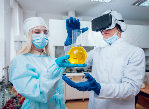 Science technician in virtual reality glasses examines the drug in laboratory.