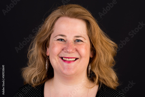 Portrait of a attractive european light overweighted red haired female in dark shirt, headshot, in front of black backgrouind