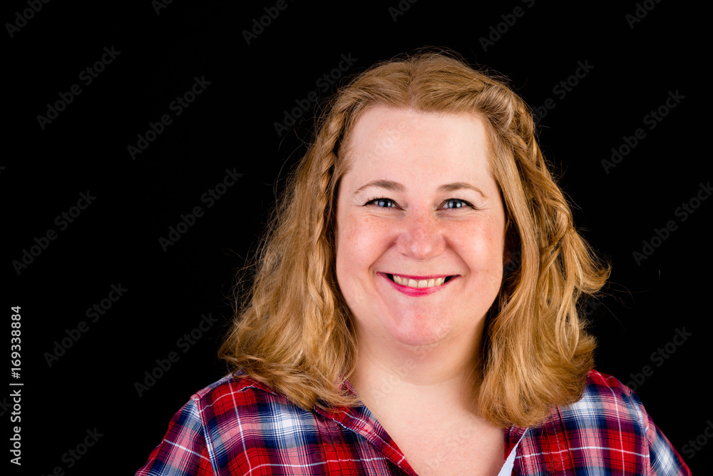 Portrait of a attractive european light overweighted red haired female with red lumberjack shirt - view on head, studio shot in fron of black background Portrait of a attractive european light overweighted red haired female with red lumberjack shirt - view on head, studio shot in fron of black background
