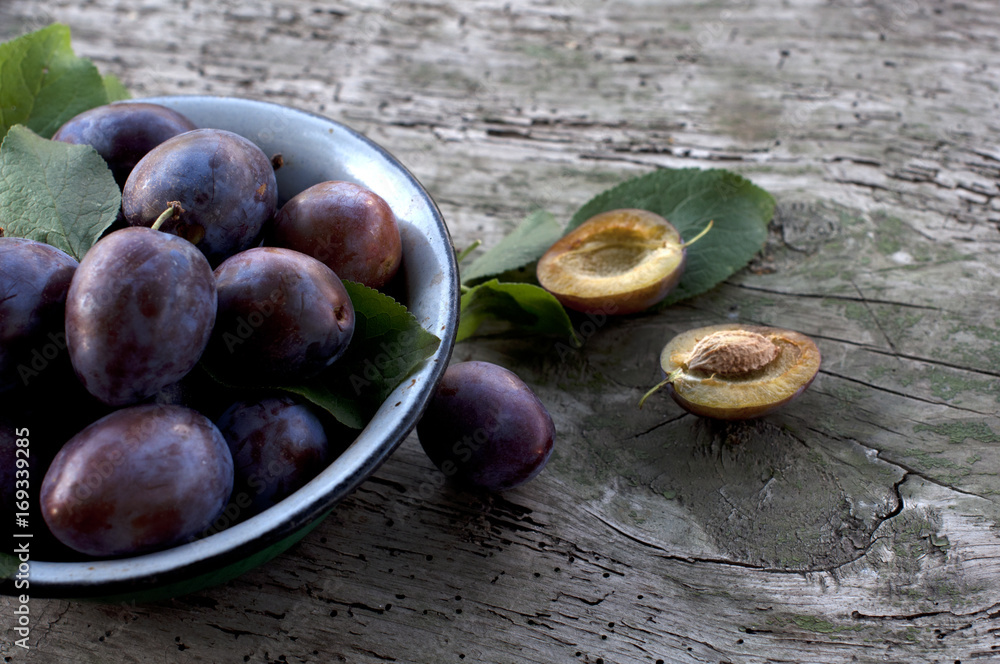 Obraz premium Ripe plums in plate on wooden background