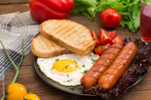 English breakfast - toast, egg, sausages and vegetables salad. Wooden rustic background. Close-up. Top view