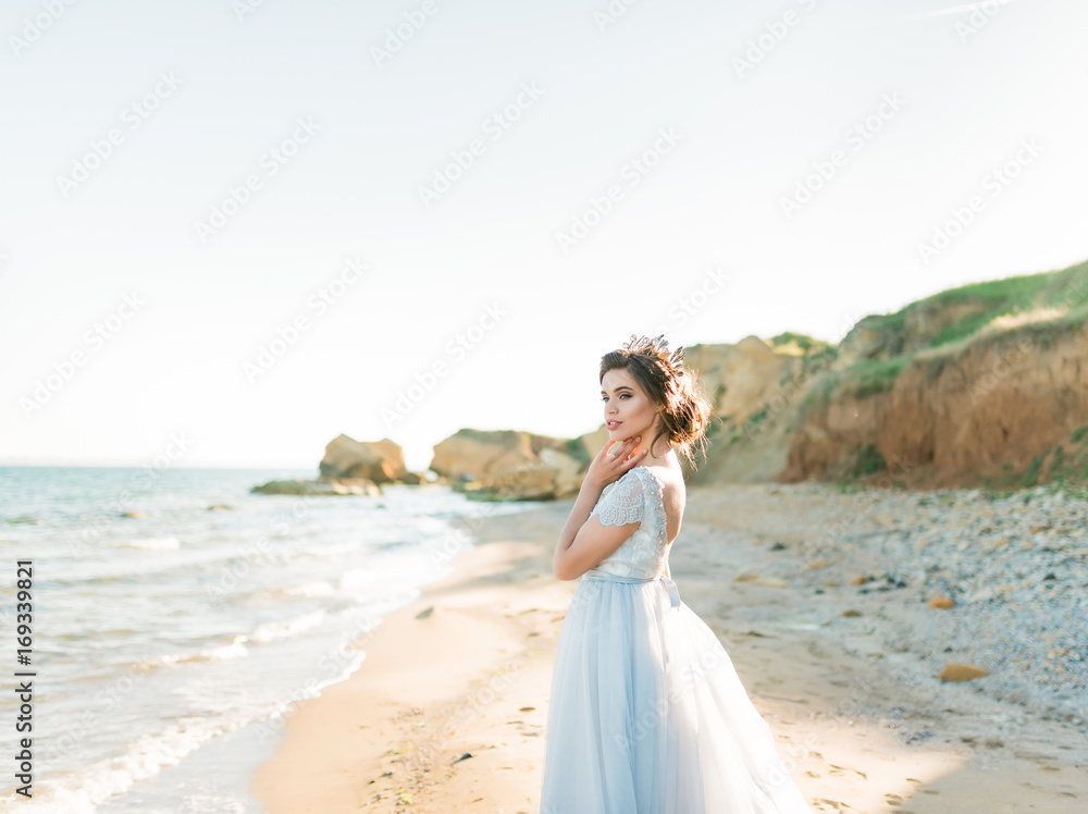 Romantic beautiful bride in luxury dress posing on the beach.