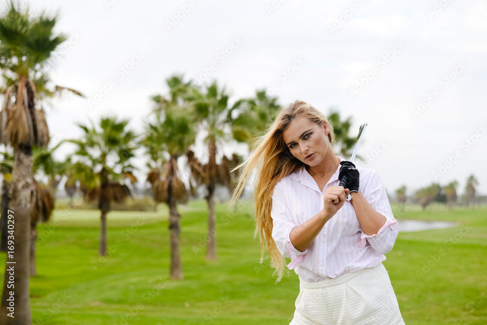 Portrait of cheerful caucasian woman holding golf club on green field outdoor background Portrait of cheerful caucasian woman holding golf club on green field outdoor background