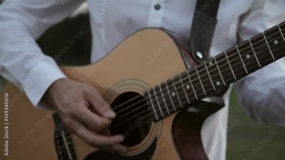 Hipster man play the guitar and sings outdoor by picturesque sunset and green background. Hipster man play the guitar and sings outdoor by picturesque sunset and green background.