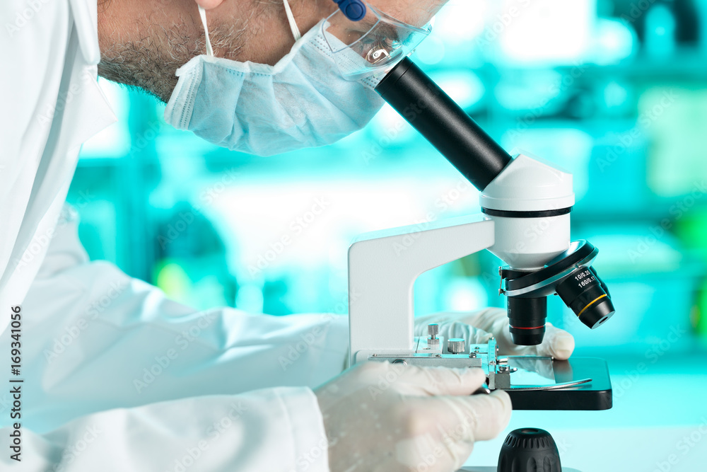 Research scientist working with specimen plate on microscope with molecule model Research scientist working with specimen plate on microscope with molecule model