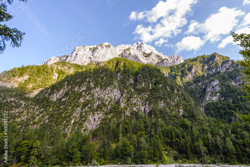 A beutiful landscape in the mountains, clouds above peaks and forest in foreground photo