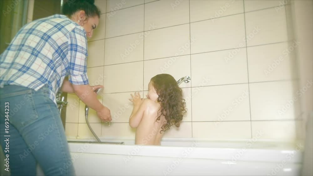 Mother washes the head of a small child. Mom washing her baby with shampoo in a bubble bath. Kid is happy when his mother pours water on his head. Mother washes the head of a small child. Mom washing her baby with shampoo in a bubble bath. Kid is happy when his mother pours water on his head.