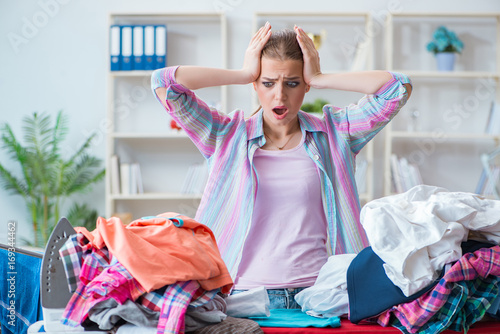 Sad woman ironing clothing at home