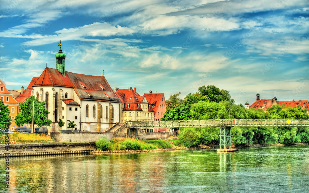 St. Oswald Church with Eiserner Steg bridge across the Danube River in Regensburg, Germany St. Oswald Church with Eiserner Steg bridge across the Danube River in Regensburg, Germany