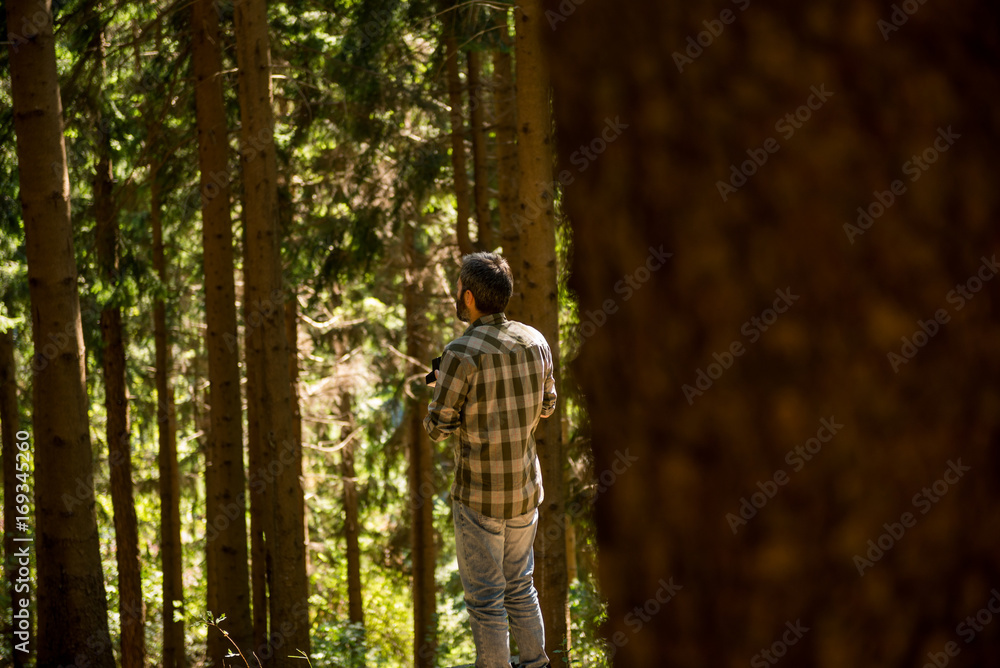 Active young adult man enjoy trekking in wild pine forest on mountain in sunny summer day outdoor