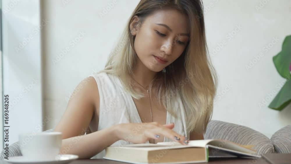 Woman looking through dictionary and drinking coffee. Woman looking through dictionary and drinking coffee.