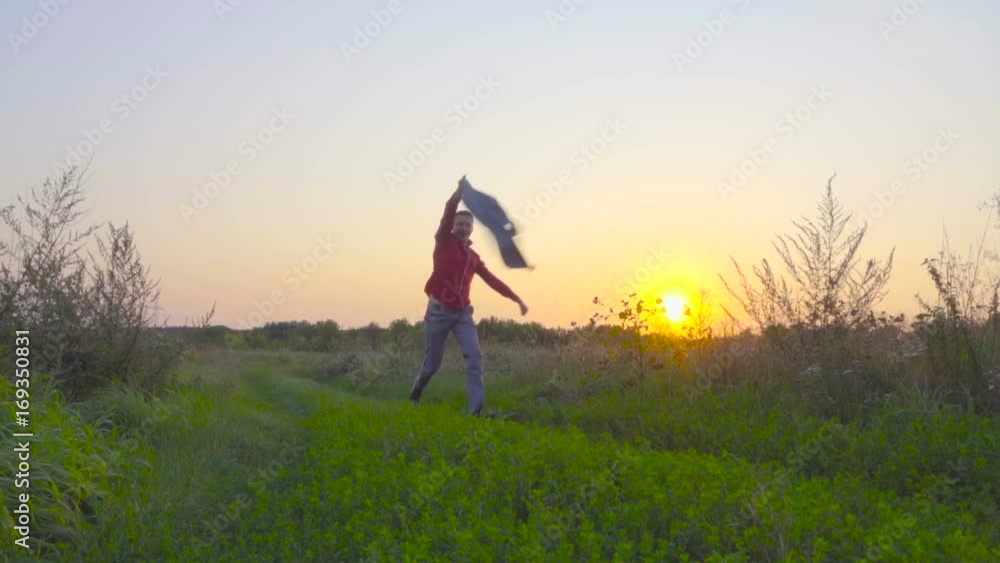 Happy free businessman running on a green meadow and swinging his jacket at sunset. Slow motion Happy free businessman running on a green meadow and swinging his jacket at sunset. Slow motion
