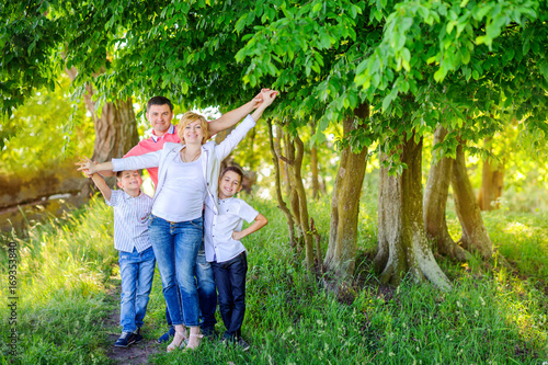 big happy family walking in the beautiful park at sunset, cuddling and having fun