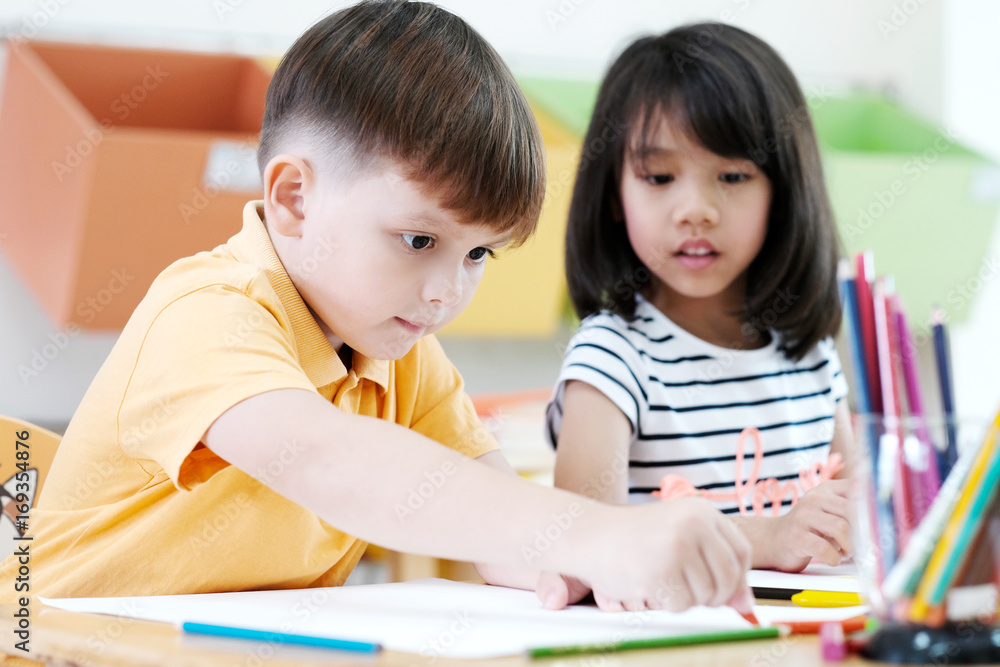 Boy drawing color pencils in kindergarten classroom, preschool and kid education concept Boy drawing color pencils in kindergarten classroom, preschool and kid education concept