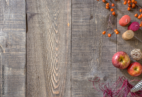 Fototapeta Naklejka Na Ścianę i Meble -  Rustic wood plank background with autumn candles, apples and berries along right side border