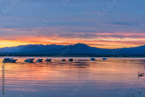 Sunset Jackson Lake - Spring sunset lights up cloudy sky over a quiet bay of Jackson Lake in Grand Teton National Park, Wyoming, USA. 