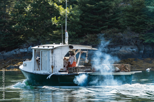 Lobster boat heads out for a beautiful days work in South Bristol, Maine, United States photo