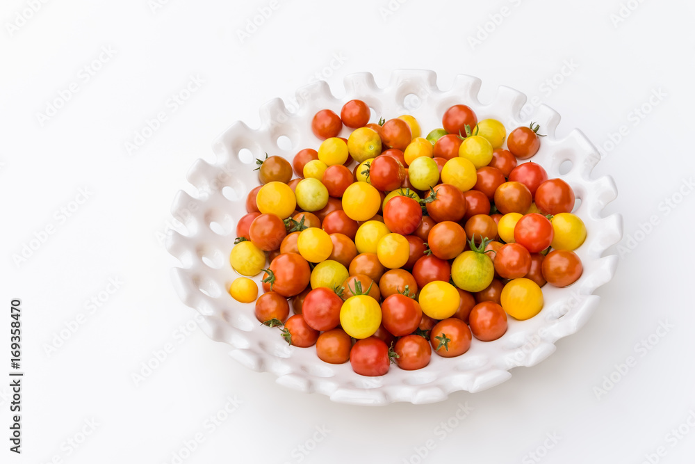 Garden harvest of yellow and red cherry tomatoes on white tray Garden harvest of yellow and red cherry tomatoes on white tray