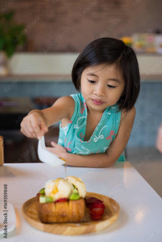 Girl eats her breakfast. On the bright wooden table summer or spring.Hands in picture top view Girl eats her breakfast. On the bright wooden table summer or spring.Hands in picture top view