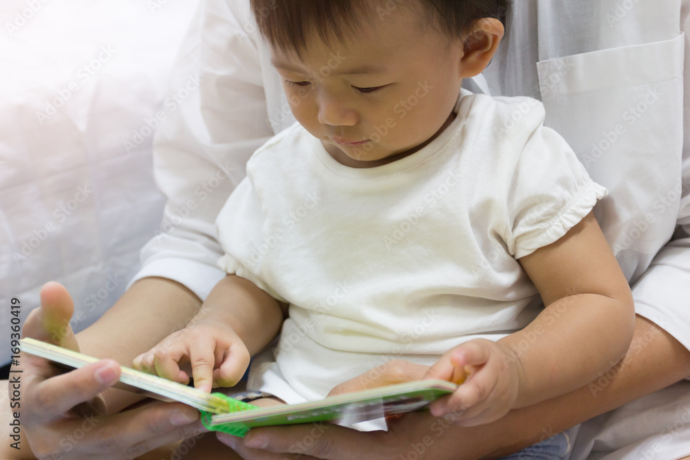 Asian adorable baby one year is looking book for kid. Asian adorable baby one year is looking book for kid.