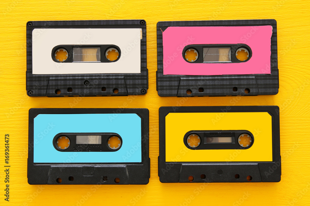 Retro cassette tape collection over yellow wooden table. top view. copy space