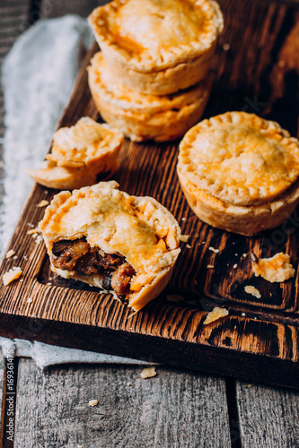 Fotografie Fresh Traditional Australian meat mini pie on the wooden board on table backgrou