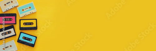 Vászonkép Retro cassette tape collection over yellow wooden table