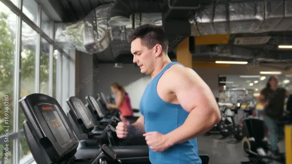 Man bodybuilder running on the treadmill in the gym - slider Man bodybuilder running on the treadmill in the gym - slider