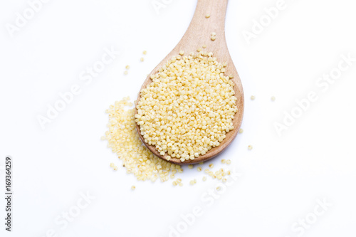 Millet groats with wooden spoon on white.