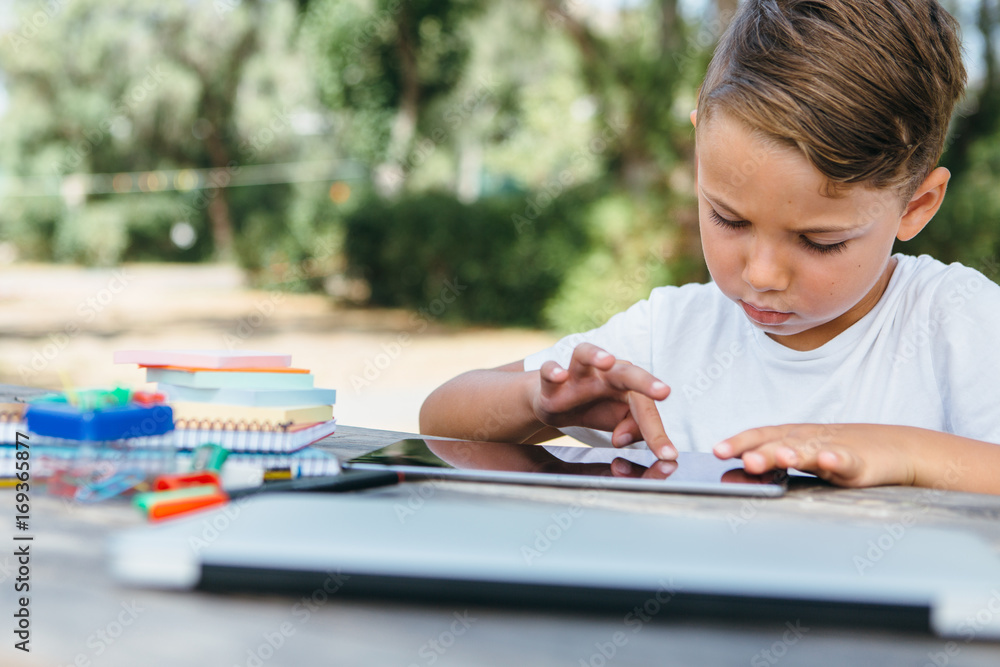 Kid browsing tablet doing homework Kid browsing tablet doing homework