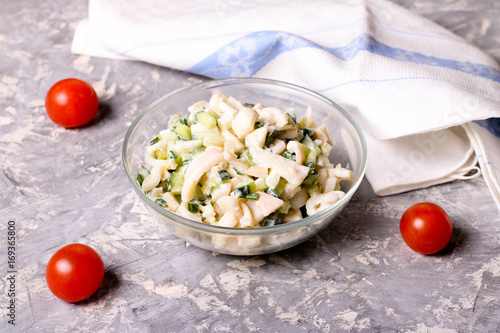 Salad with squid, egg and cucumber in a glass bowl