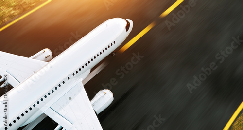 White commercial airplane taking off on the airport runway at sunset. Passeng...