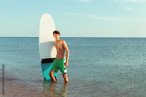 Handsome surfer holding his surfboard