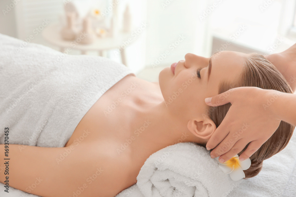 Young woman enjoying of facial massage in spa salon