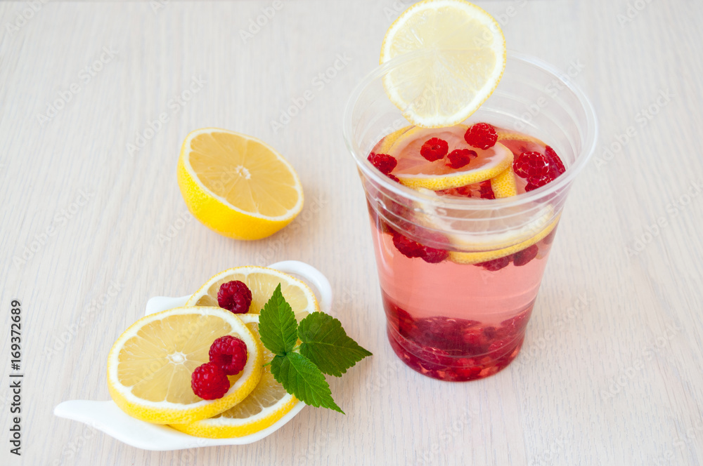 Lemon slices, drink, berries and raspberry leaves Lemon slices, drink, berries and raspberry leaves
