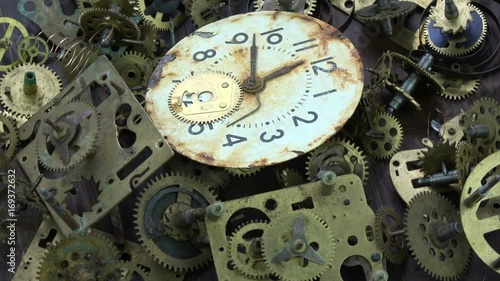 Vintage analog clock brass gears and cogs with rusty white dial clock face rotating background

