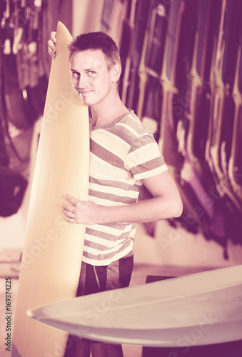 male is posing with surfboard in store on the beach. © JackF