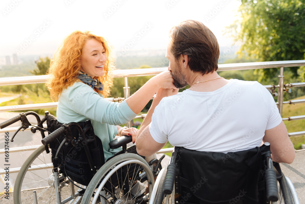 Senior loving disabled man kissing a hand of his wife