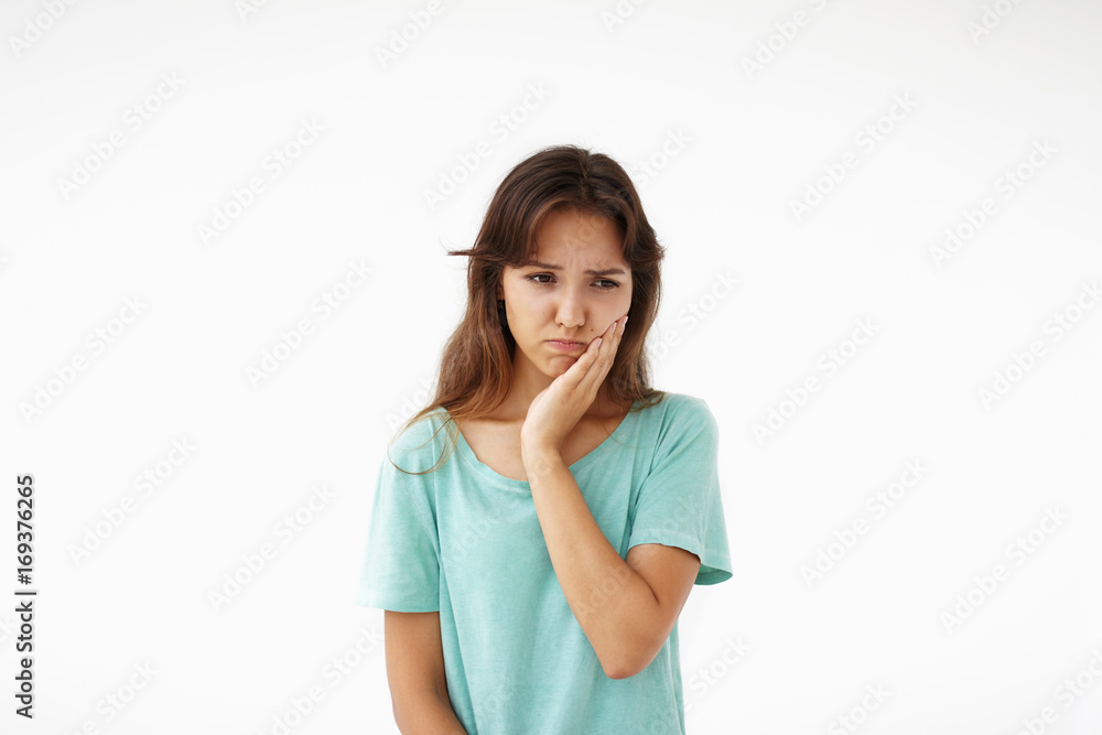 People, illness, sickness and health problems concept. Picture of unhappy young mixed race woman having sad painful expression on her face, suffering from bad toothache, holding hand on her cheek People, illness, sickness and health problems concept. Picture of unhappy young mixed race woman having sad painful expression on her face, suffering from bad toothache, holding hand on her cheek