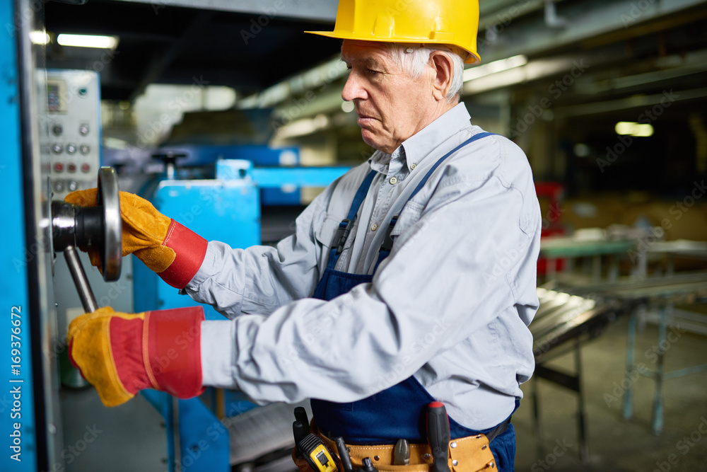 Portrait of senior mechanic repairing machines in workshop of modern factory Portrait of senior mechanic repairing machines in workshop of modern factory