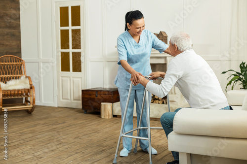 Joyful delighted caregiver smiling to her patient