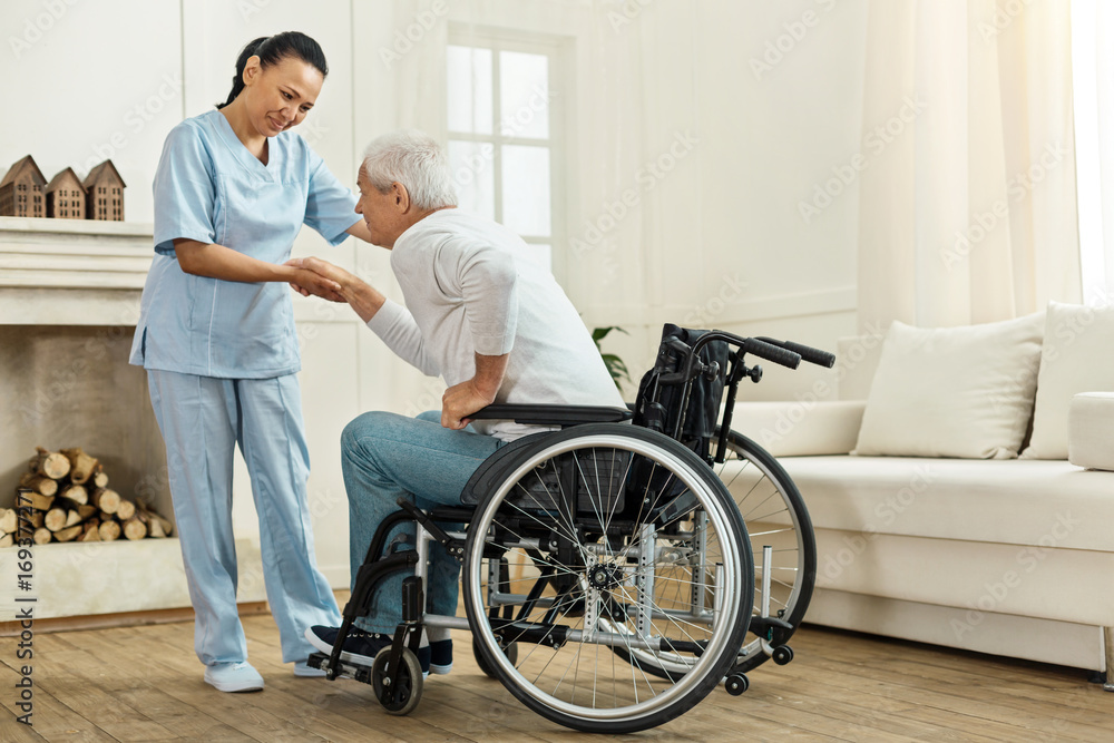 Joyful helpful caregiver holding her patients hand Joyful helpful caregiver holding her patients hand