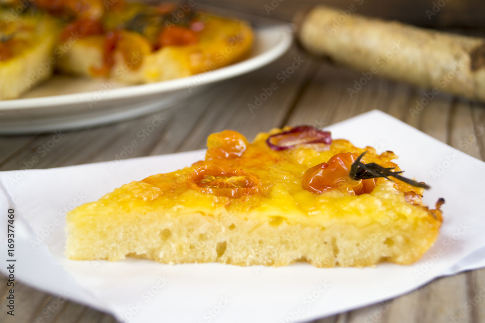 Rustic cake with cheese and cherry tomatoes on a wooden table.