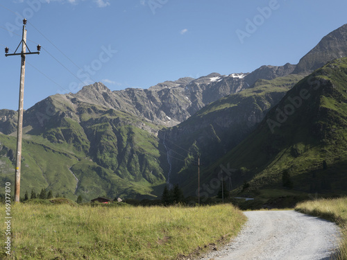 Scenic Alpine rocky alpine valley of Sportgastein in summer with row of power lines and electricity pole. Picturesque mountain pasturelands, great mountain massif and sunny weather.