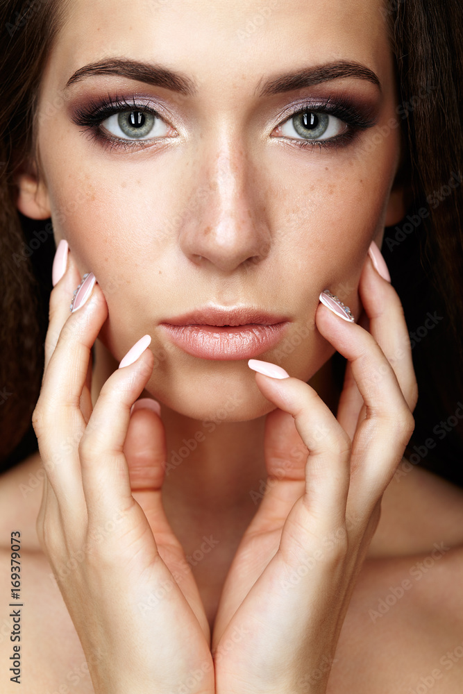Beauty portrait of young woman touching face with fingers. Brunette girl with long hair and day female makeup Beauty portrait of young woman touching face with fingers. Brunette girl with long hair and day female makeup