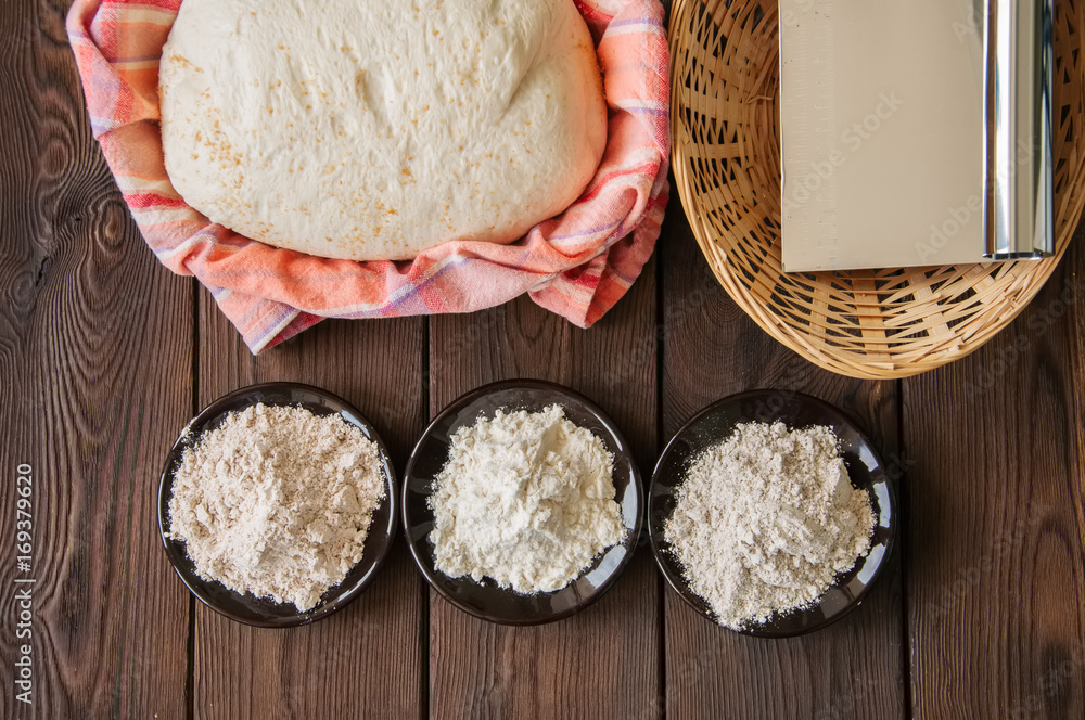 Homemade dough, sourdough in a jar, mix of flours, bread and basket for proof and spatula on a wooden background. Baking concept. Homemade dough, sourdough in a jar, mix of flours, bread and basket for proof and spatula on a wooden background. Baking concept.