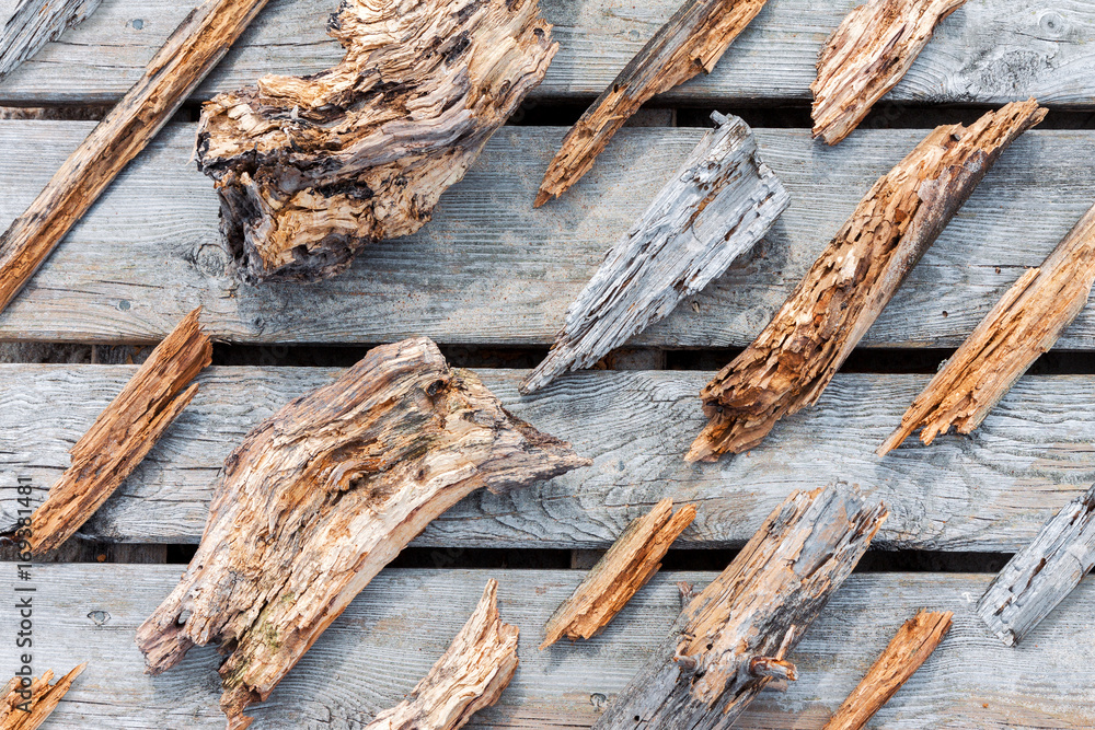 Fototapeta premium Old rotten wooden pieces and fragments well organized on wooden plank background, top view