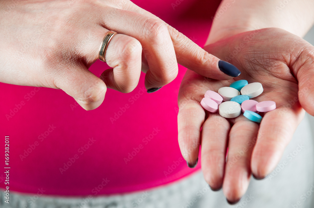 Young girl mixing pills and vitamins by finger on her palm, horizontal image Young girl mixing pills and vitamins by finger on her palm, horizontal image