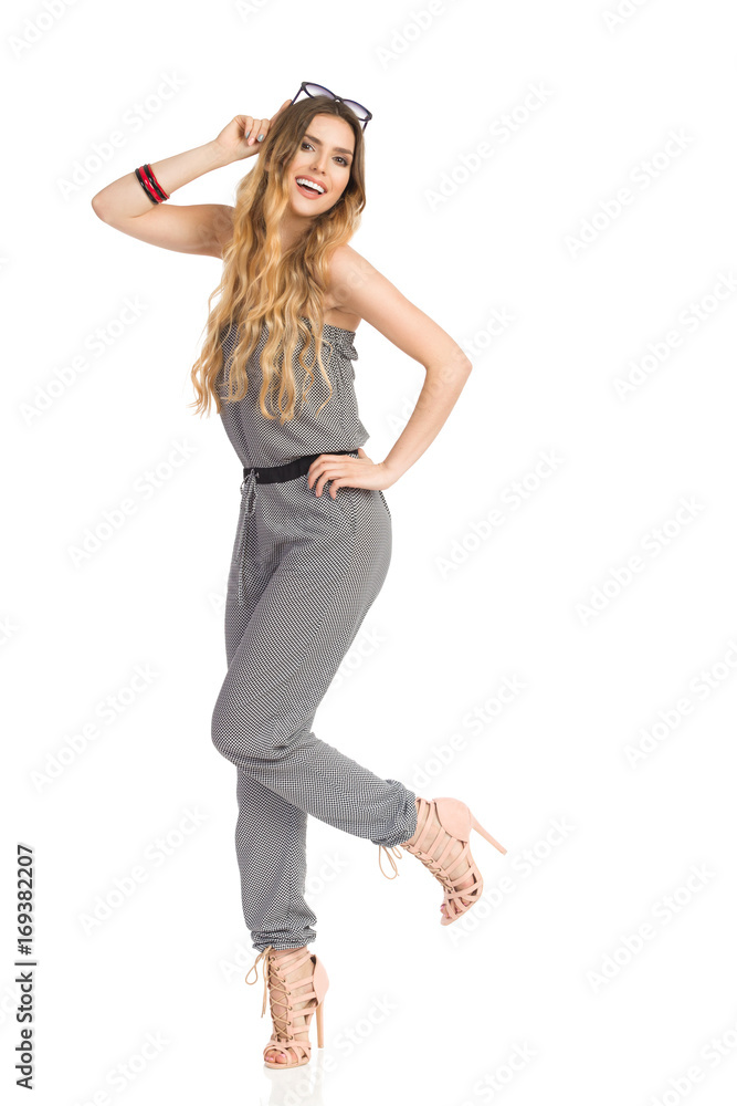 Carefree Young Woman In Jumpsuit Is Standing On One Leg And Smiling Carefree Young Woman In Jumpsuit Is Standing On One Leg And Smiling